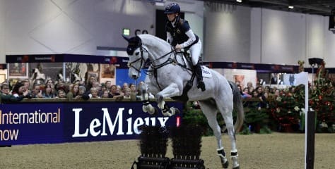 Laura Collett jumping cross country fence on grey horse